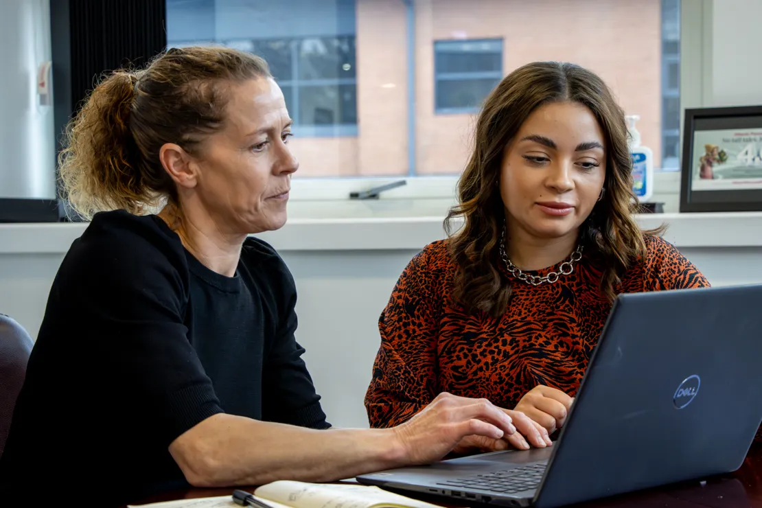 Two woman in a meeting discussing a document open on their laptop