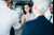 Businesswoman shaking hands with a man in a white shirt, with colleagues standing around them